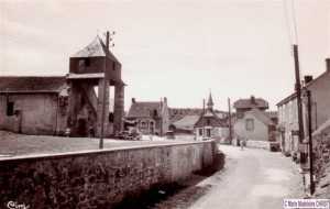 Une Peugeot 403 est garée au pied du porche de l'église.